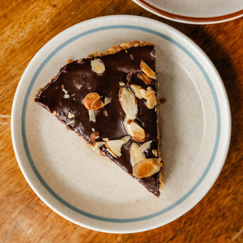 A slice of Almond joy pie on a white plate on a wooden table