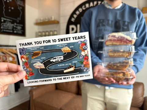 Person holding a pie with a 'Thank you for 10 sweet years' card in a home setting.