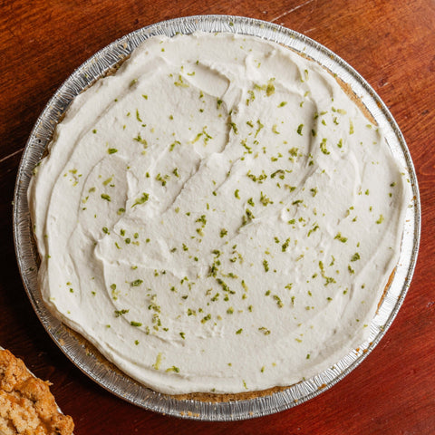 A pie on a wooden table, one with a creamy top.