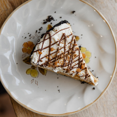 Slice of peanut butter pie on a plate with black coffee on the side.