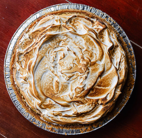 Topped pie with meringue on a wooden surface