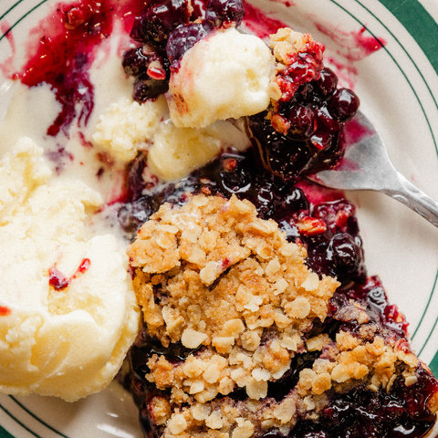 Sliced dessert with berry topping and crumbly texture on a plate with a fork.