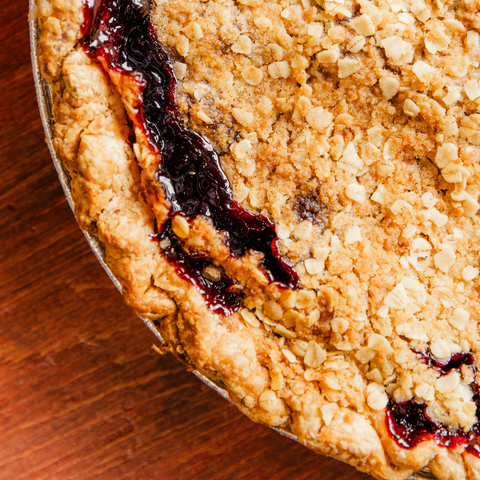 Close-up of a pie with a crumbly crust and jelly filling on a wooden surface