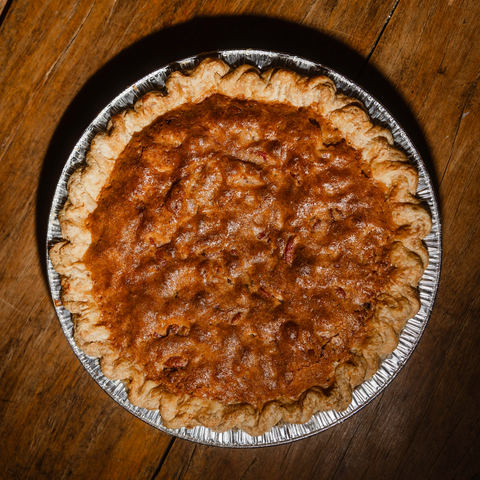 A freshly baked cookie dough pie in a silver aluminum pie dish, photographed from directly above on a rustic dark wood table.