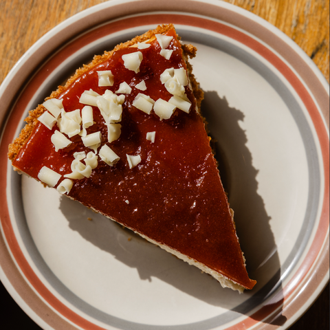 Slice of cheesecake with guava paste and white chocolate shavings on a plate.