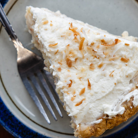 Slice of coconut cream pie on a plate with a fork